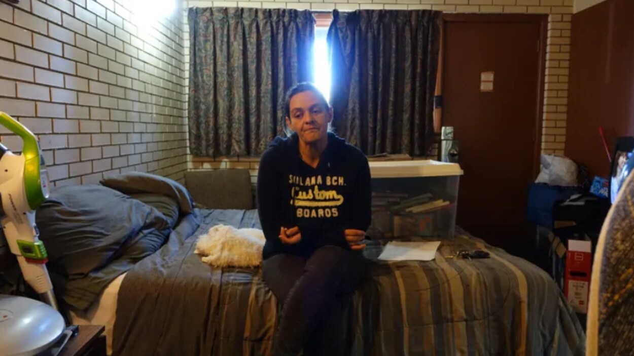 Une femme assise sur un lit dans une chambre de motel à Ottawa.