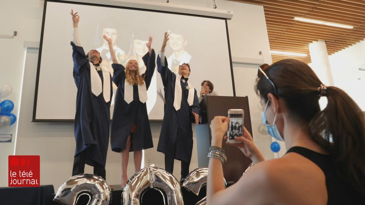 Trois finissants les bras en l'air lors d'une cérémonie de remise de diplômes.