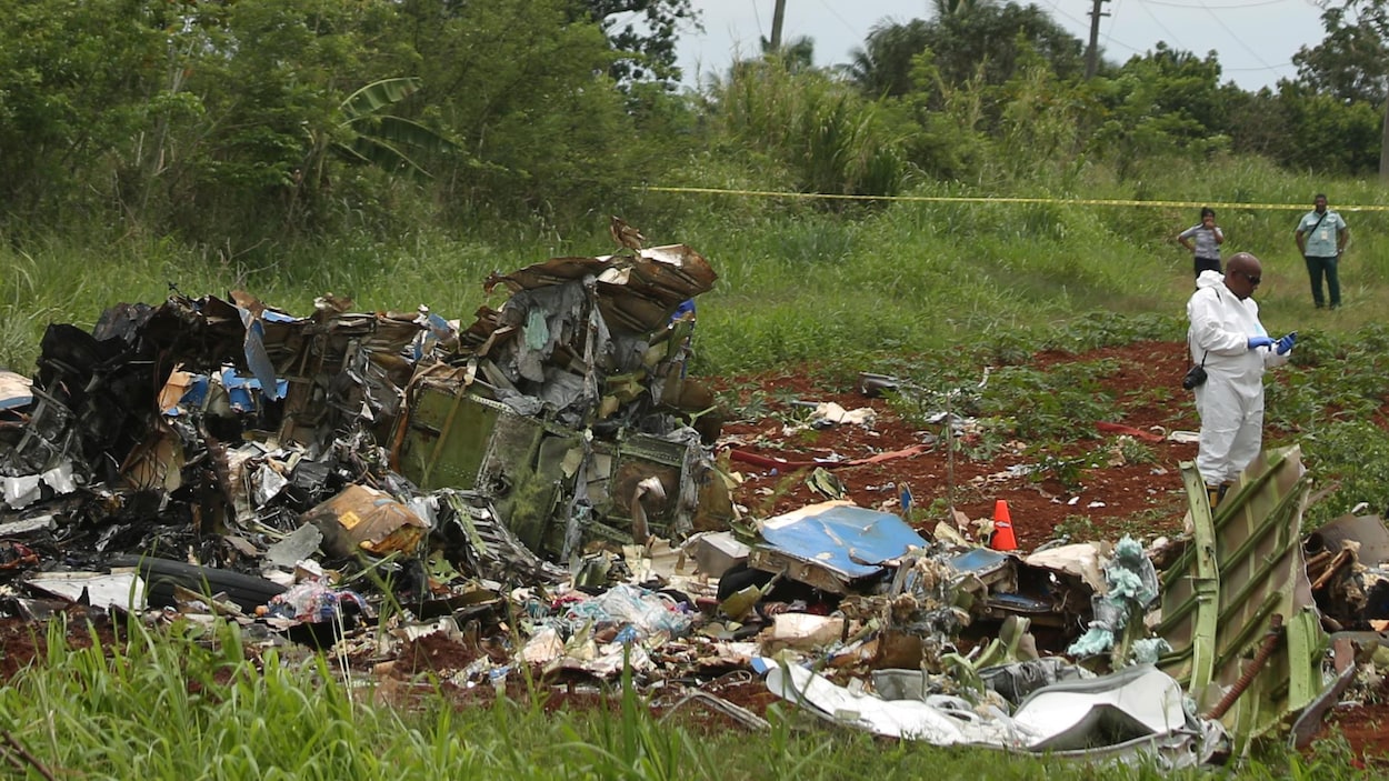 Un membre des services d'urgence se tient près des débris de l'écrasement d'un avion près de La Havane, qui a fait 110 morts. Un membre des services d'urgence se tient près des débris de l'écrasement d'un avion près de La Havane, qui a fait 110 morts.