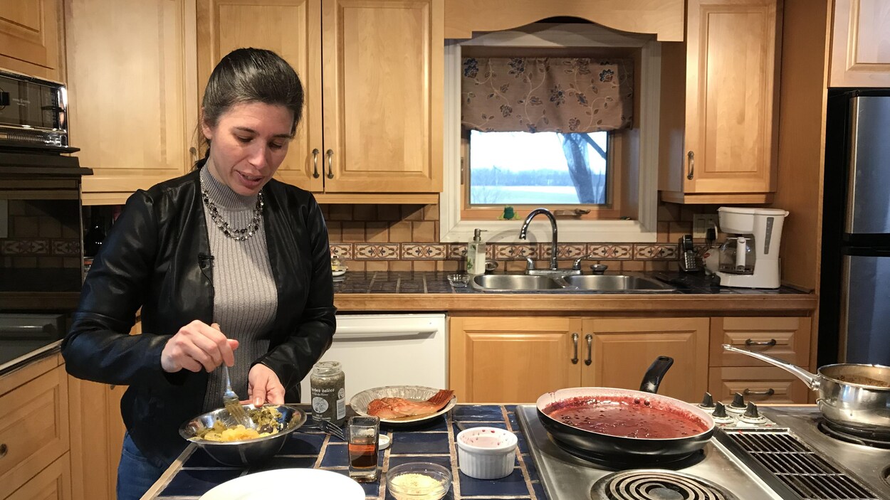 Le chef autochtone Lysanne O'Bomsawin est au comptoir d'une cuisine en train de mélanger de la nourriture dans un bol, alors qu'à ses côtés, des chaudrons sont sur les ronds d'une cuisinière, en attente.