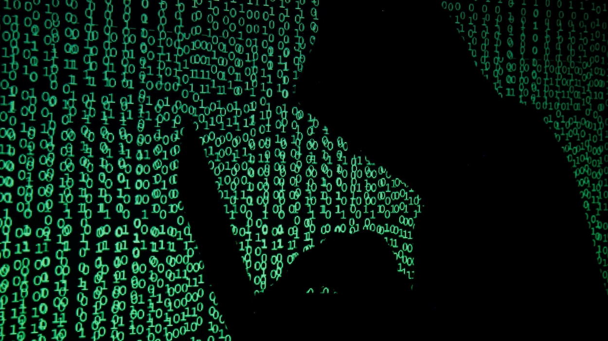 L'ombre d'un pirate informatique est projetée sur un fond de chiffres, des 0 et des 1.