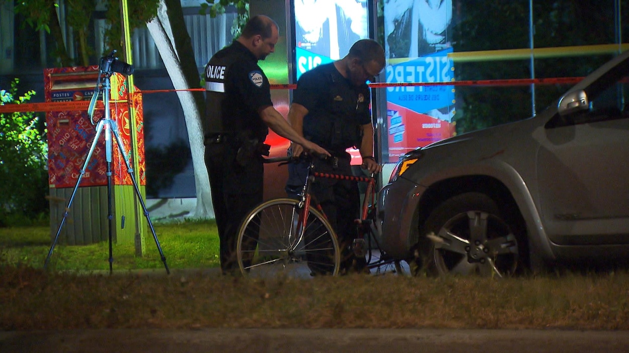Des policiers inspectent le vélo de la victime. Des policiers inspectent le vélo de la victime.