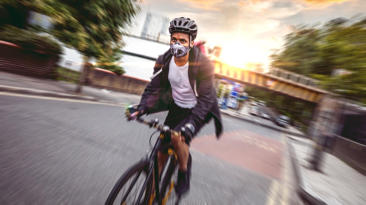Un cycliste circule avec un masque dans une rue de Londres.