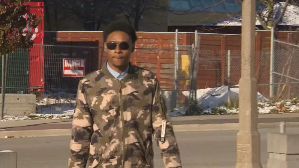 Un jeune homme noir portant des lunettes de soleil dans une rue.