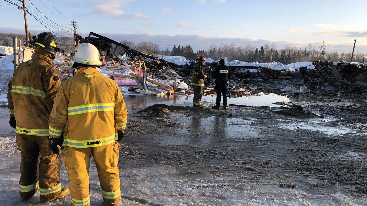 Quatre pompiers examinent les ruines