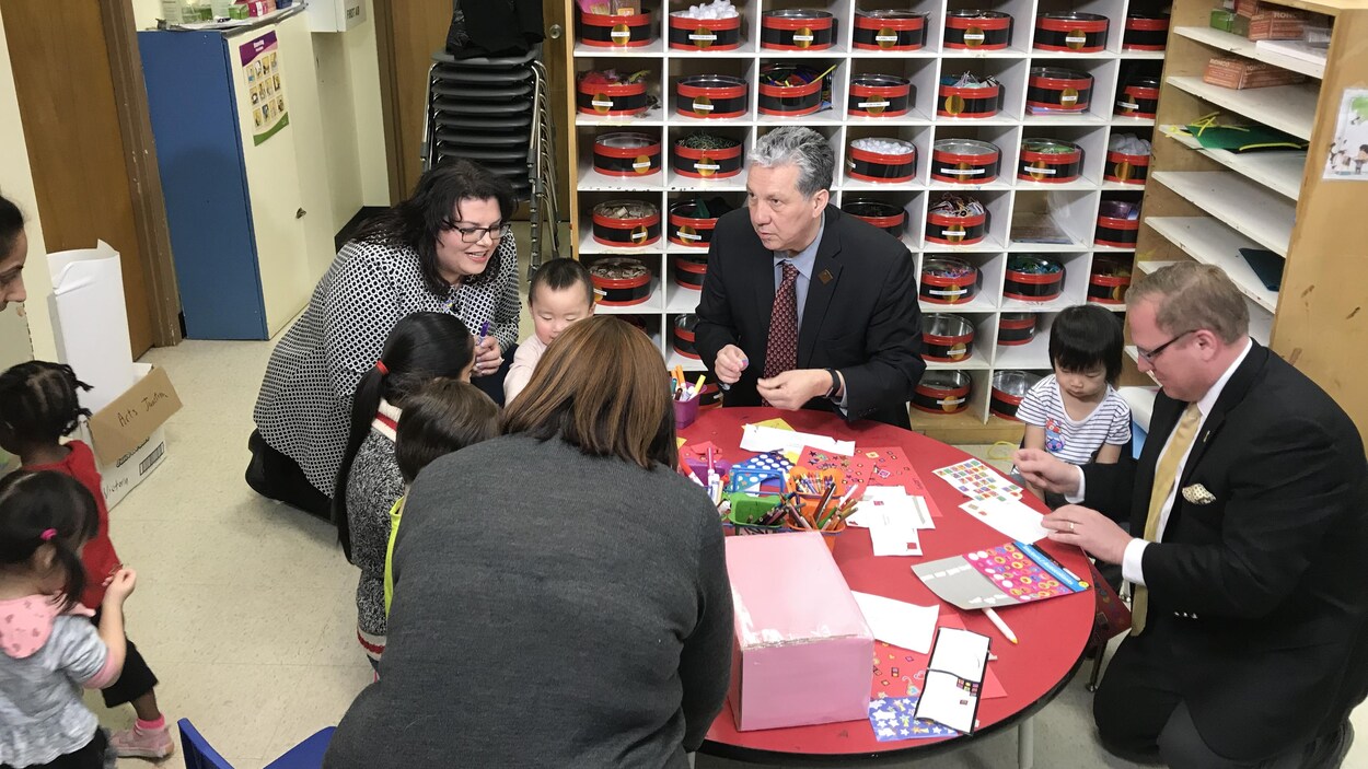 Le ministre des Familles du Manitoba Scott Fielding et le député pour Saint-Boniface-Saint-Vital Dan Vandal sont agenouillés avec des enfants de garderie.