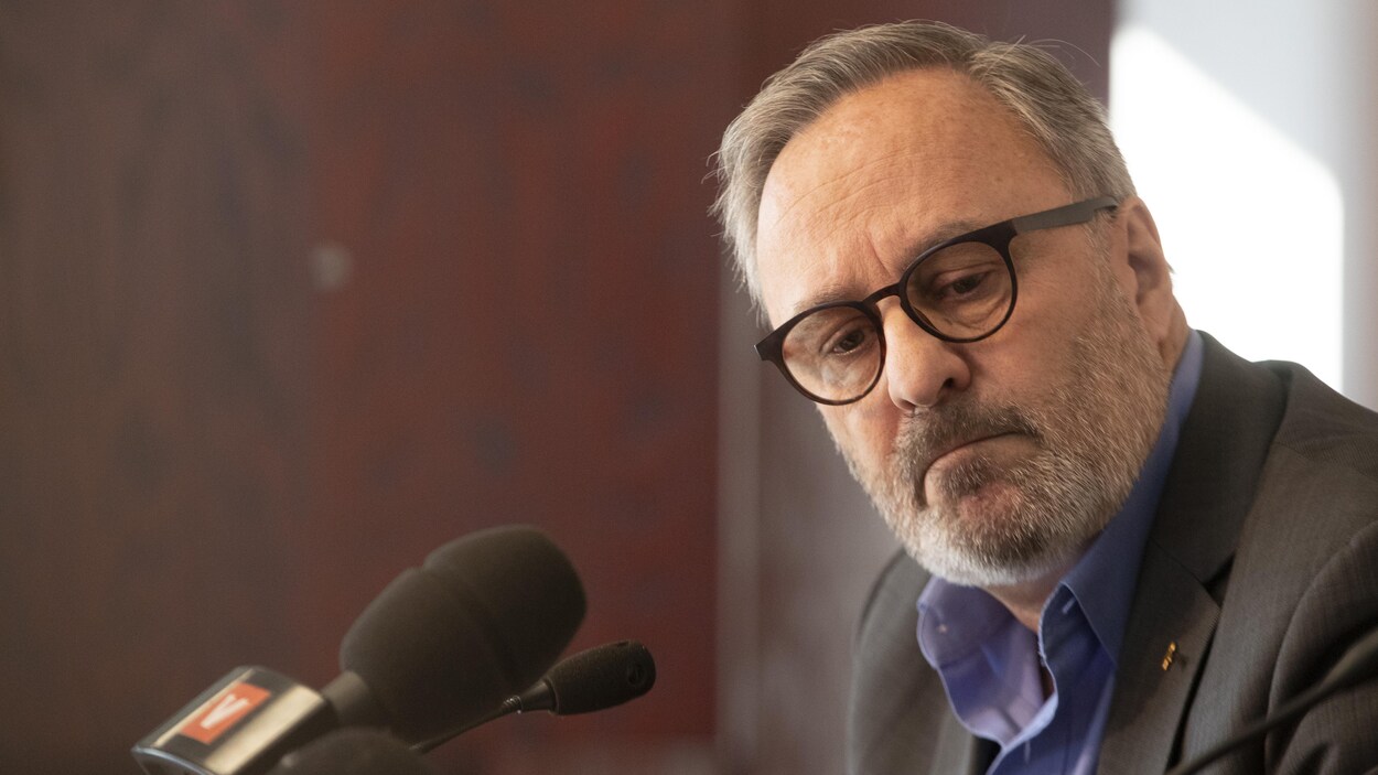 Gros plan de Daniel Boyer, avec des micros devant lui.