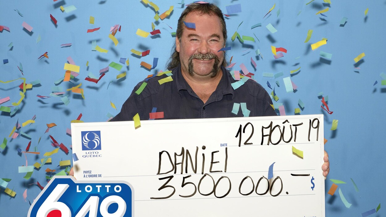 Daniel Lavoie tient un gros chèque de carton indiquant son lot de 3,5 M$.