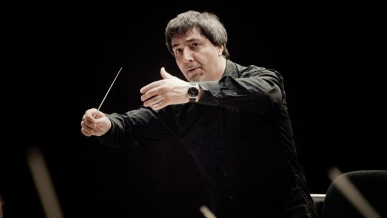 Daniel Raiskin dirige un orchestre à l'aide de mouvements de mains. Daniel Raiskin dirige un orchestre à l'aide de mouvements de mains.