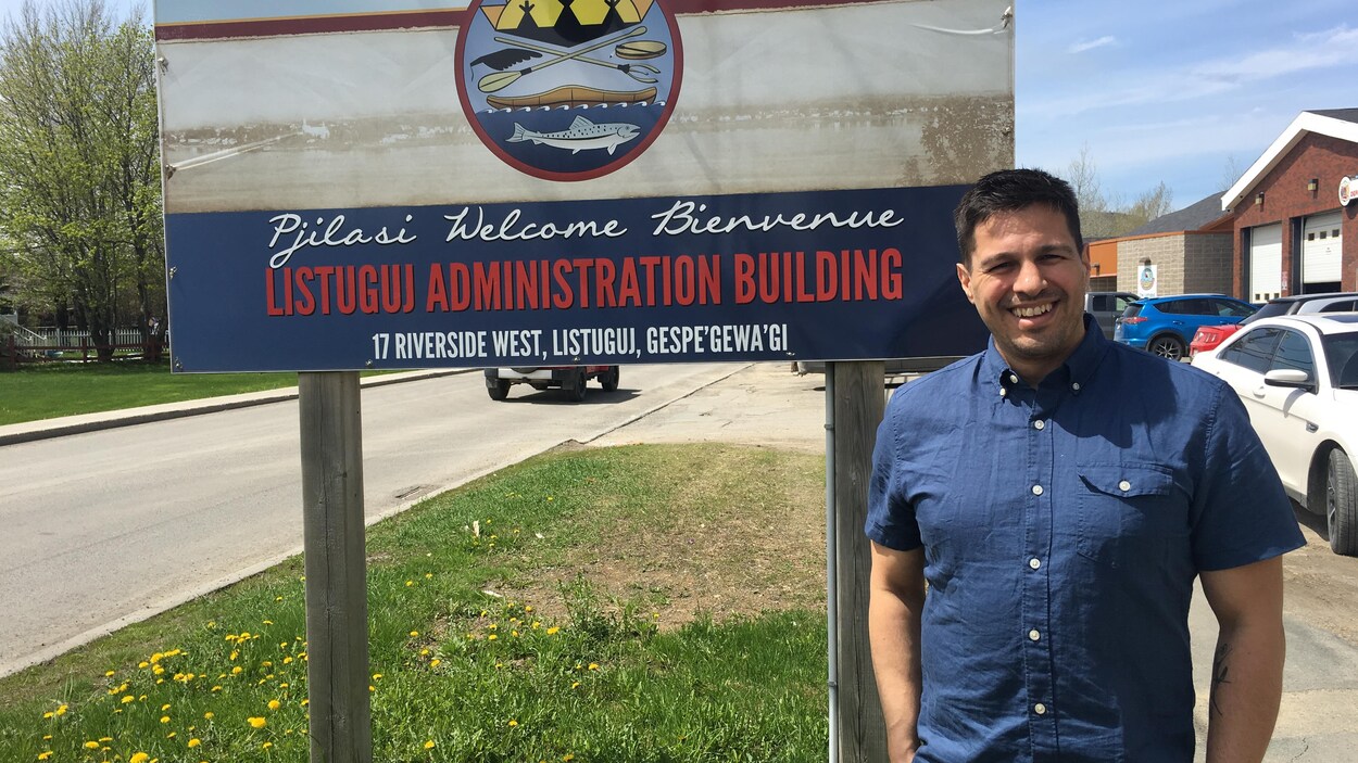 Darcy Gray pose devant une enseigne de la communauté de Listuguj.