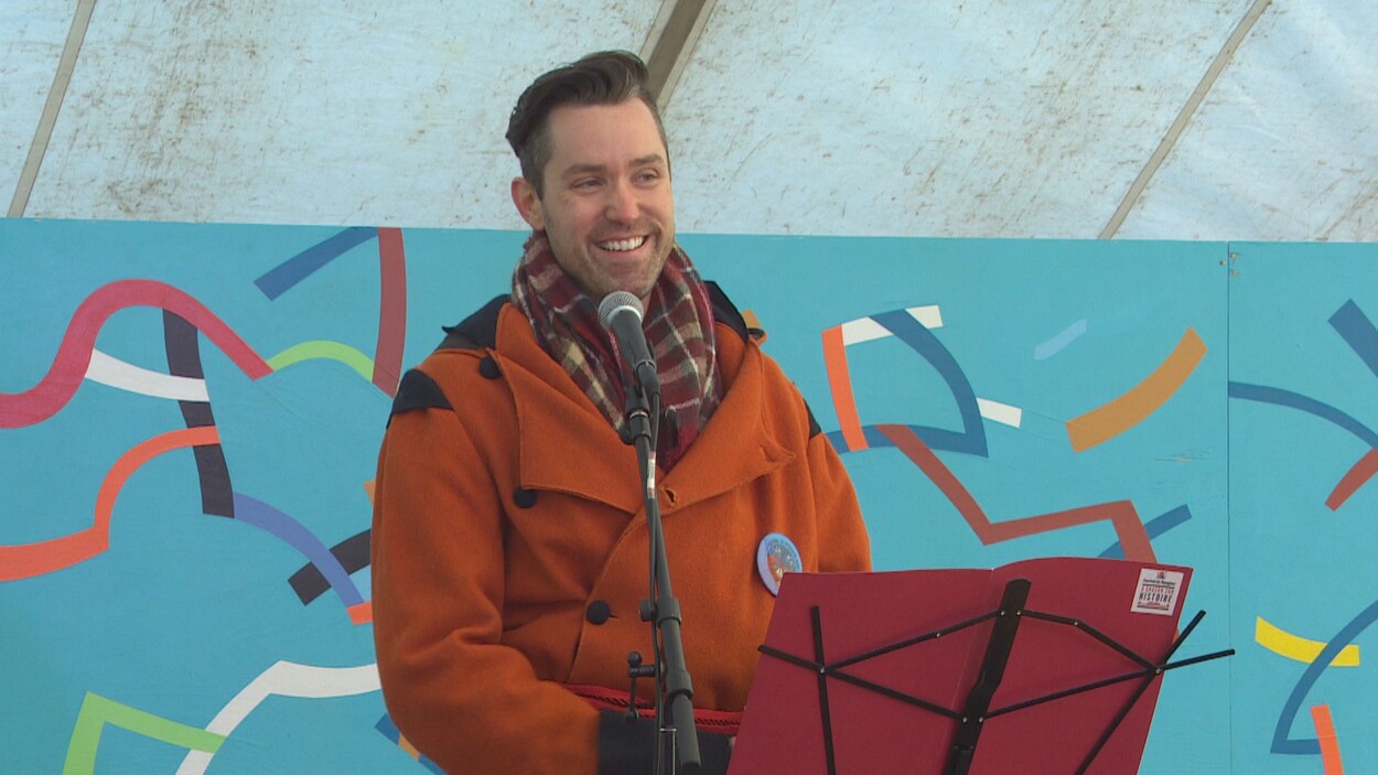 Darrel Nadeau, parle devant un micro, habillé en voyageur.