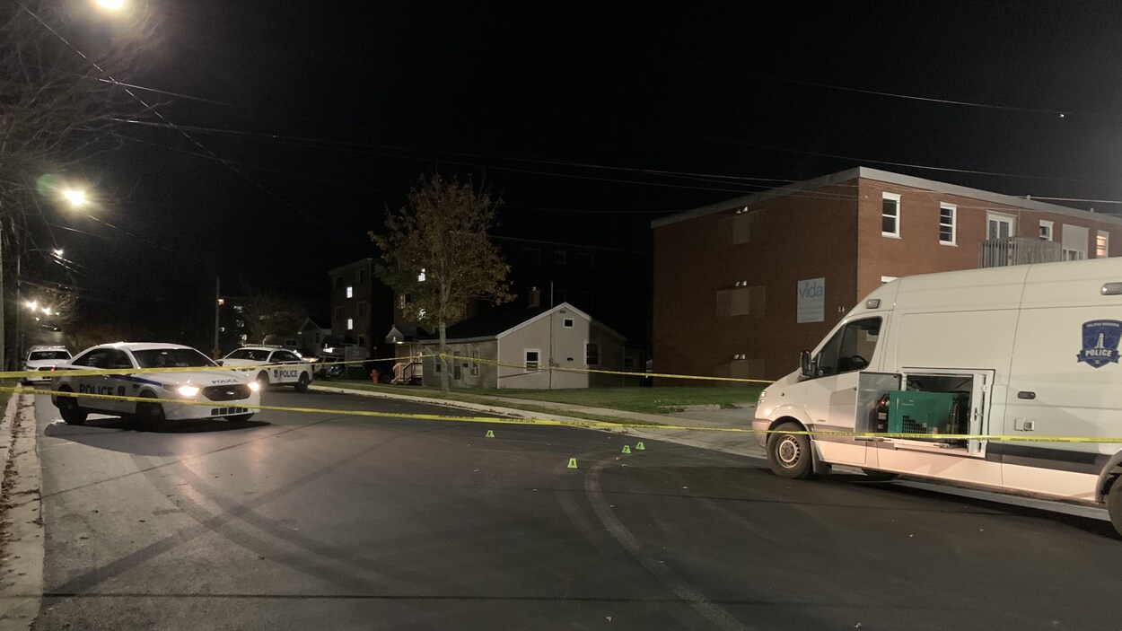 Un cordon et quatre véhicules de la police dans la rue.