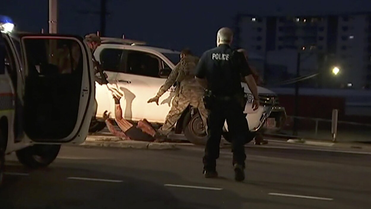 Des policiers procèdent à l'arrestation d'un suspect sur le sol à côté d'un camion blanc, à Darwin, en Australie.