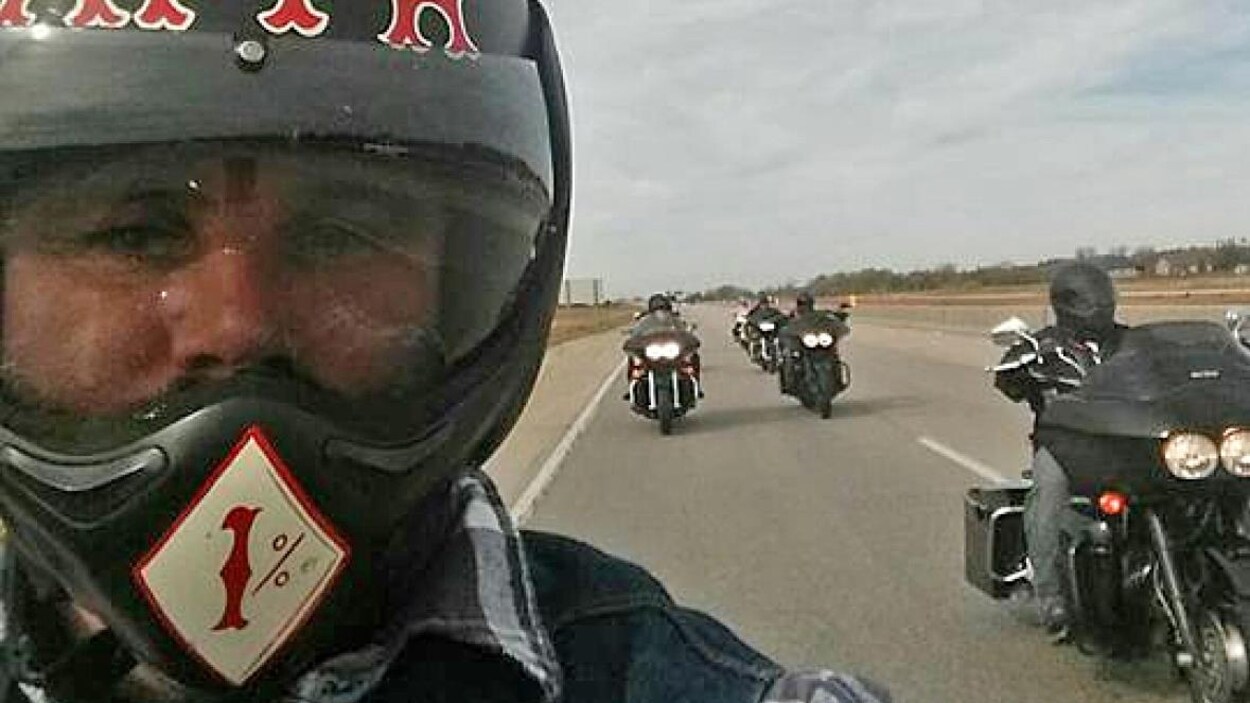 Un égoportrait d'un homme sur sa moto devant plusieurs autres motocyclistes.