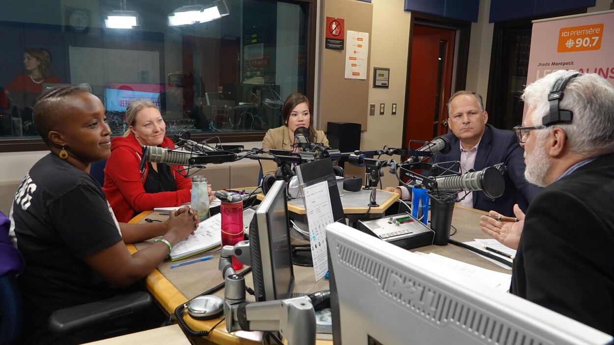 Les candidats sont réunis autour de la table dans le studio et regardent l'animateur Philippe Marcoux.
