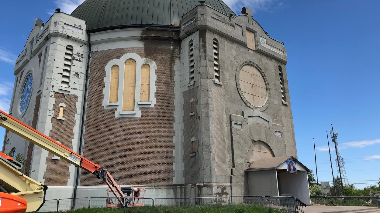 Une nacelle est stationnée devant la cathédrale d'Amos, dont des fenêtres sont barricadées.