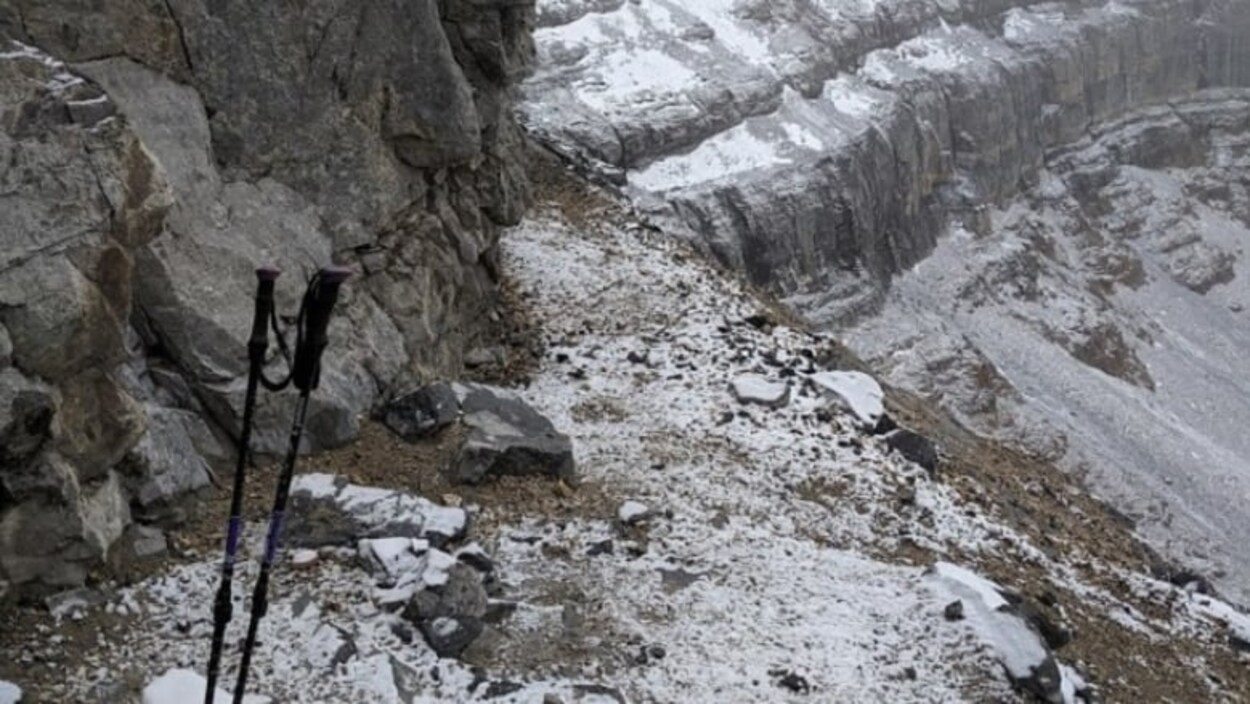 Paysage de montagne rocheuse avec des bâtons de marche en avant-plan.