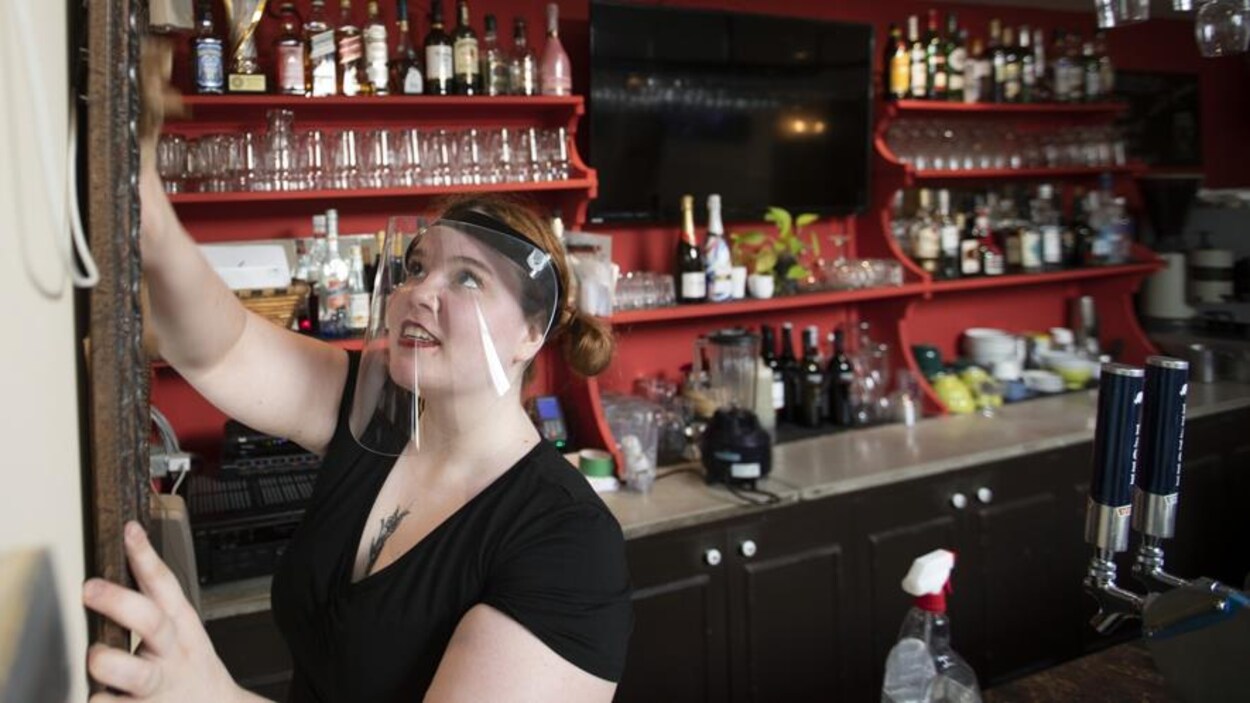 Une femme portant un masque arrange le comptoir de son restaurant.