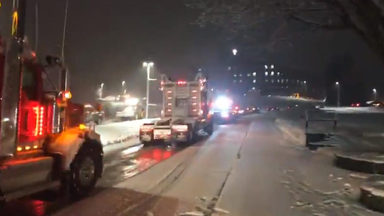 Des camions circulent devant un CHSLD le soir.