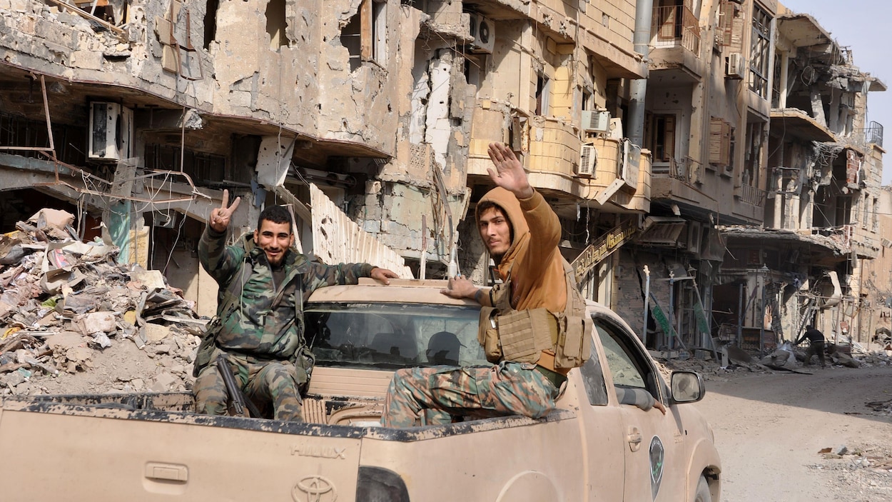 Deux combattants armés dans la boîte d'une camionnette en marche. Deux combattants armés dans la boîte d'une camionnette en marche.