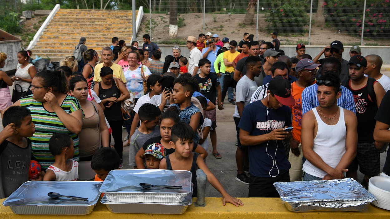 Des hommes, des femmes et des enfants attendent en file.
