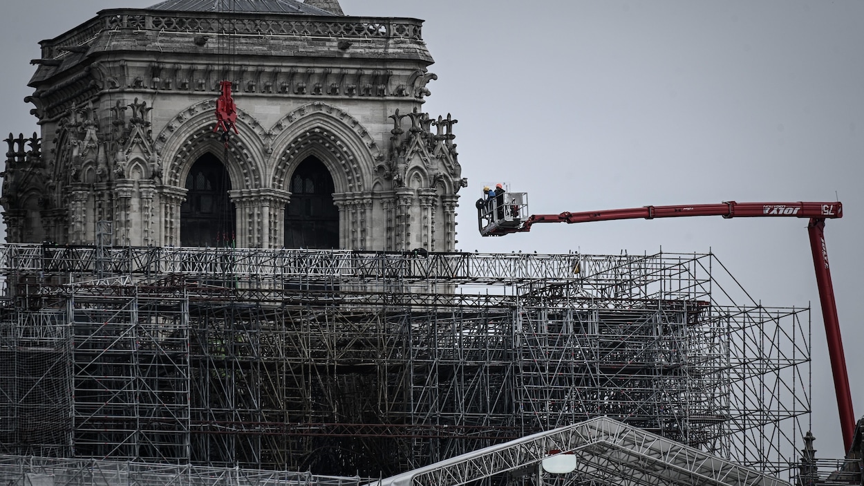 Une nacelle est au-dessus d'un gigantesque échafaudage, près des beffrois de la cathédrale.