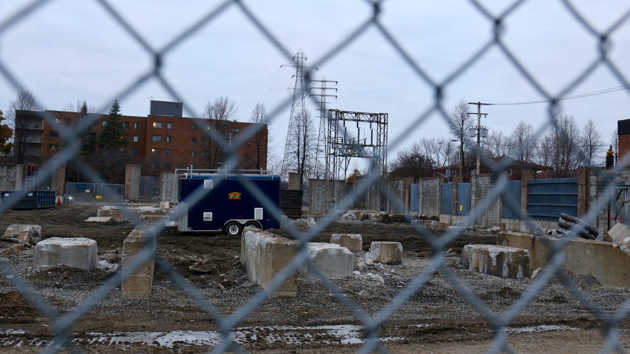 Un terrain de terre avec des blocs de béton. Au loin on voit des pylônes électriques d'Hydro-Québec.