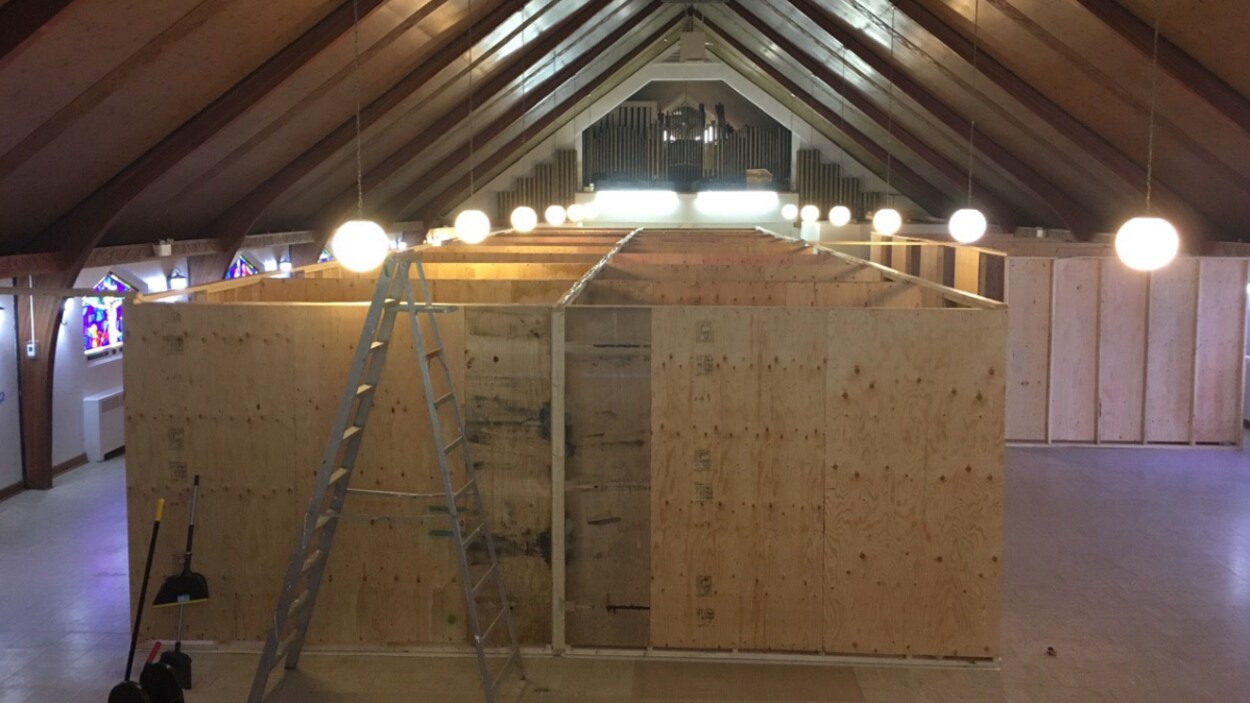 De larges panneaux de contreplaqué délimitent des chambres individuelles de fortune dans une église.