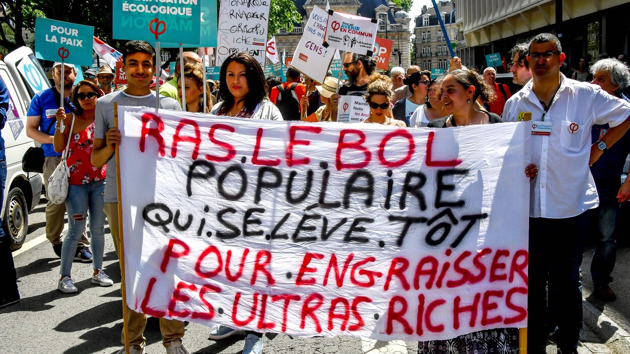 Sur le panneau tenu par des manifestants, on peut lire : « Ras le bol populaire qui se lève tôt pour engraisser les ultras riches ».
