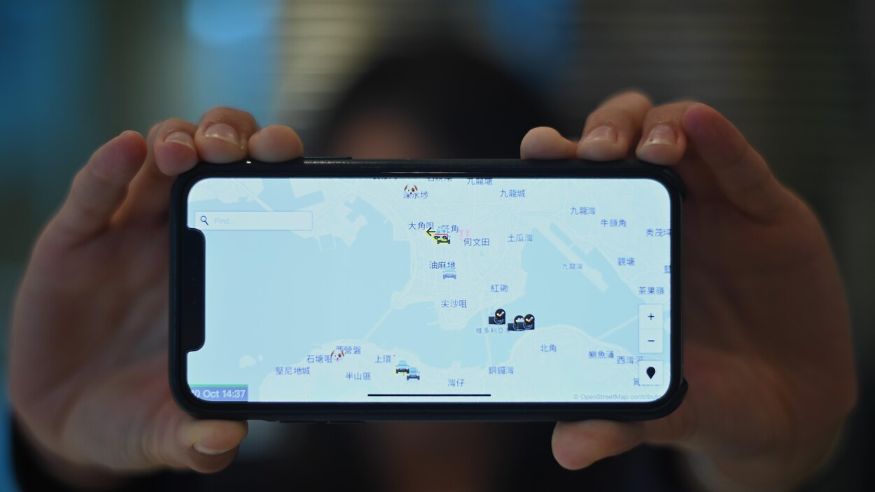 Une manifestante honkongaise tient un iPhone qui affiche l'application HKmap.live.