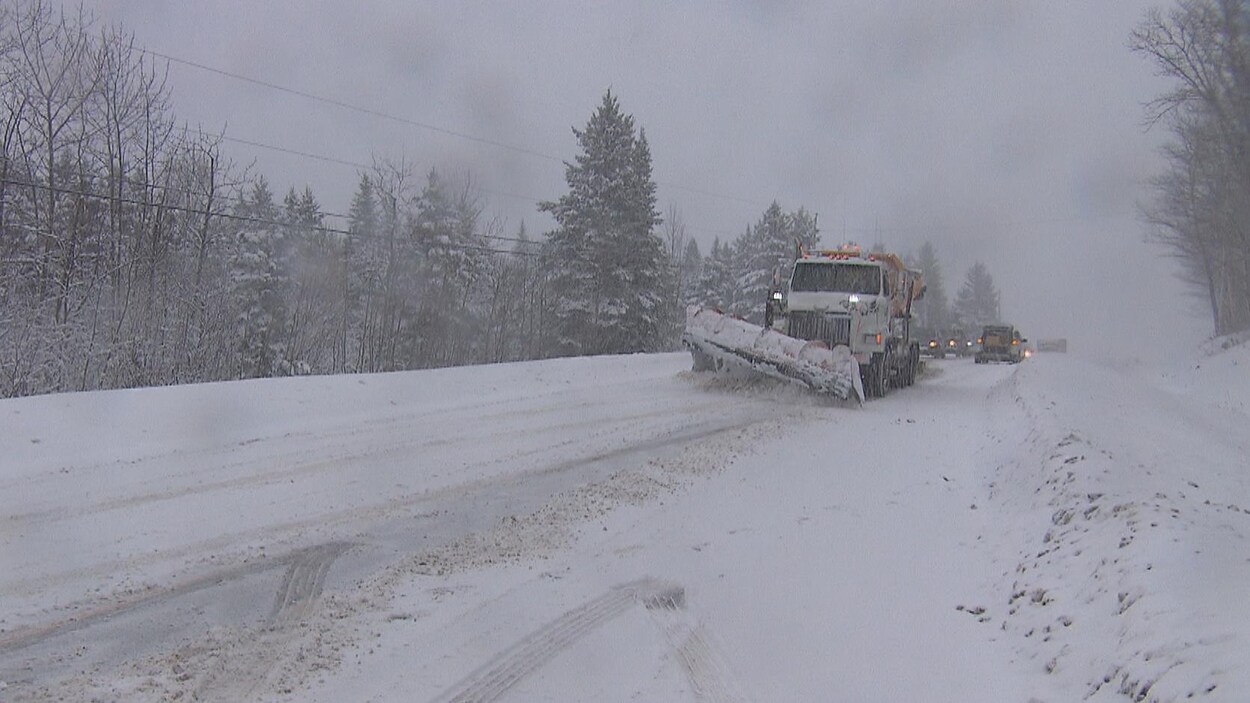 Un camion de déneigement circule sur la route 170 enneigée.