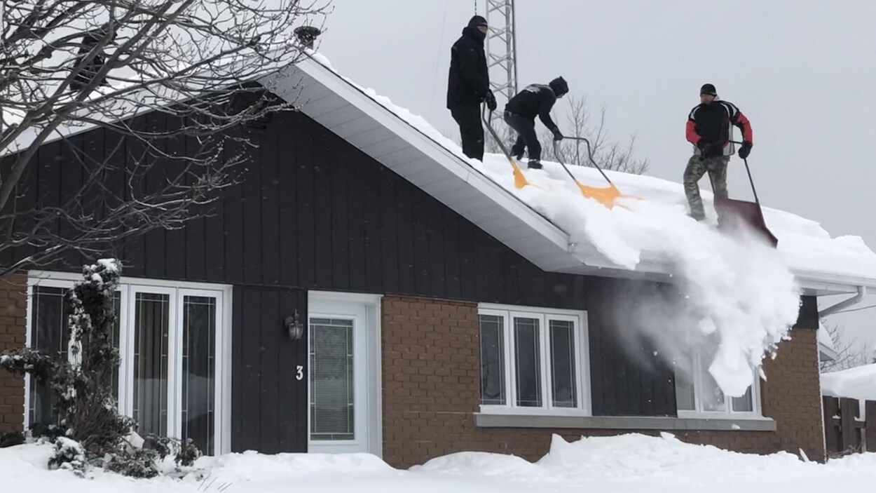Des gens déneigent une toiture à Trois-Rivières