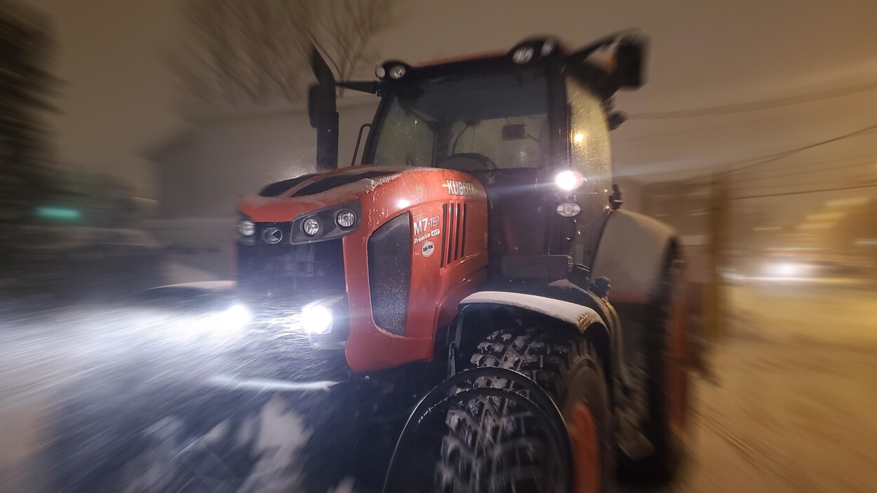 Un tracteur souffle la neige, ses phares allumés, dans la tempête, à la nuit tombée, le 12 novembre 2019.