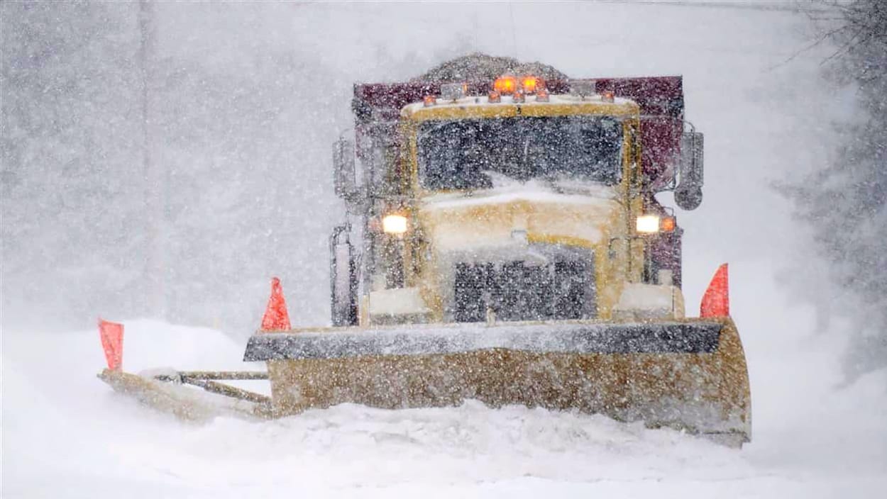 Un camion de déneigement dégage une route dans la tempête Un camion de déneigement dégage une route dans la tempête