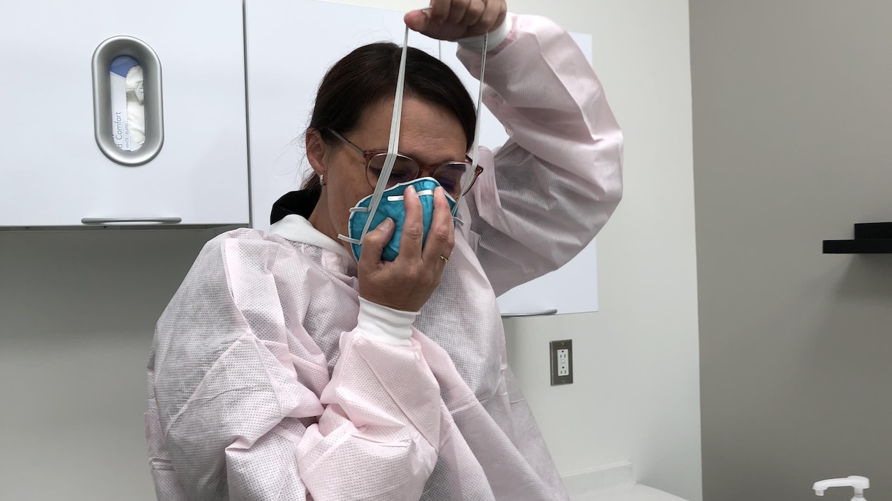 Une hygiéniste installe un masque sur son visage.