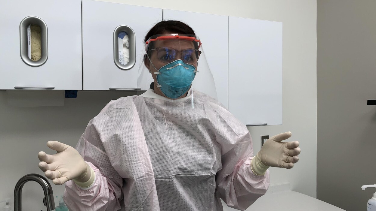 Une hygiéniste dentaire montre tout son équipement de protection.