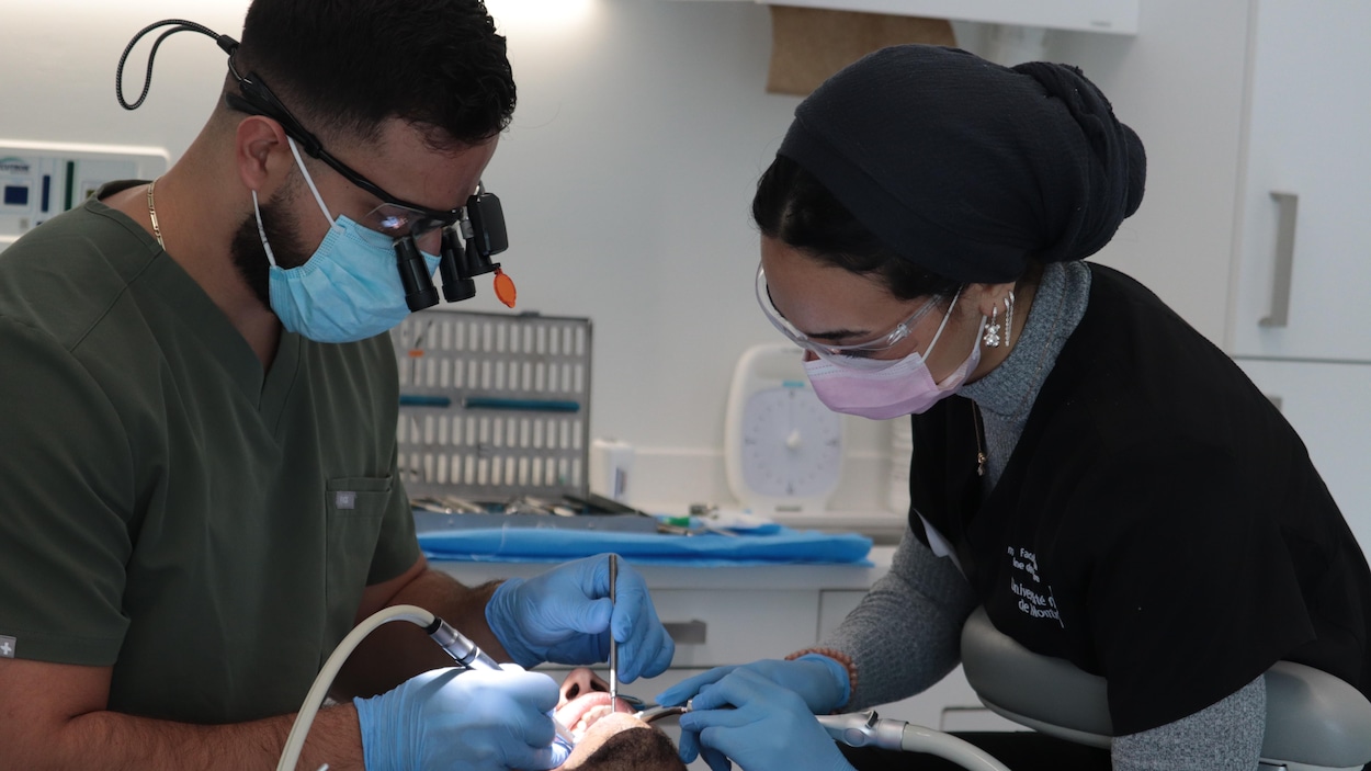 Un dentiste et une assistante dentaire travaillent dans la bouche d'un patient.