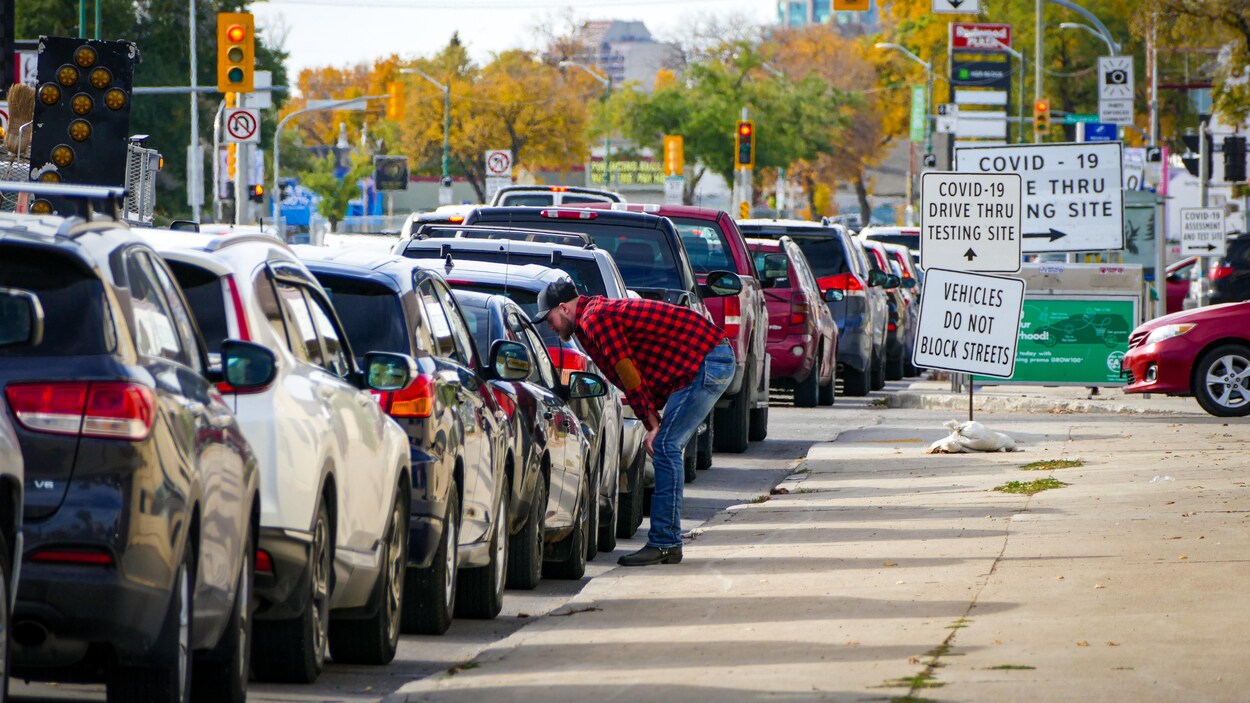Des gens dans leur voiture sont dans une longue file pour se faire dépister.