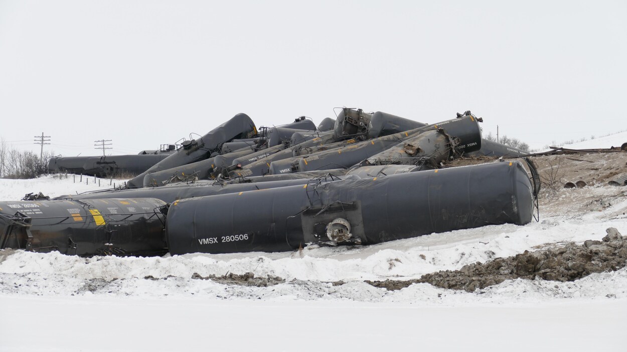 Gros plan sur les wagons de pétrole, empilés les uns sur les autres, dans un champ enneigé.