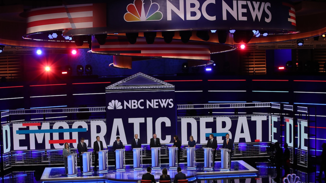Les 10 candidats participant au débat sur la scène, sur laquelle on voit les mots « débat démocrate » et le logo de NBC News.