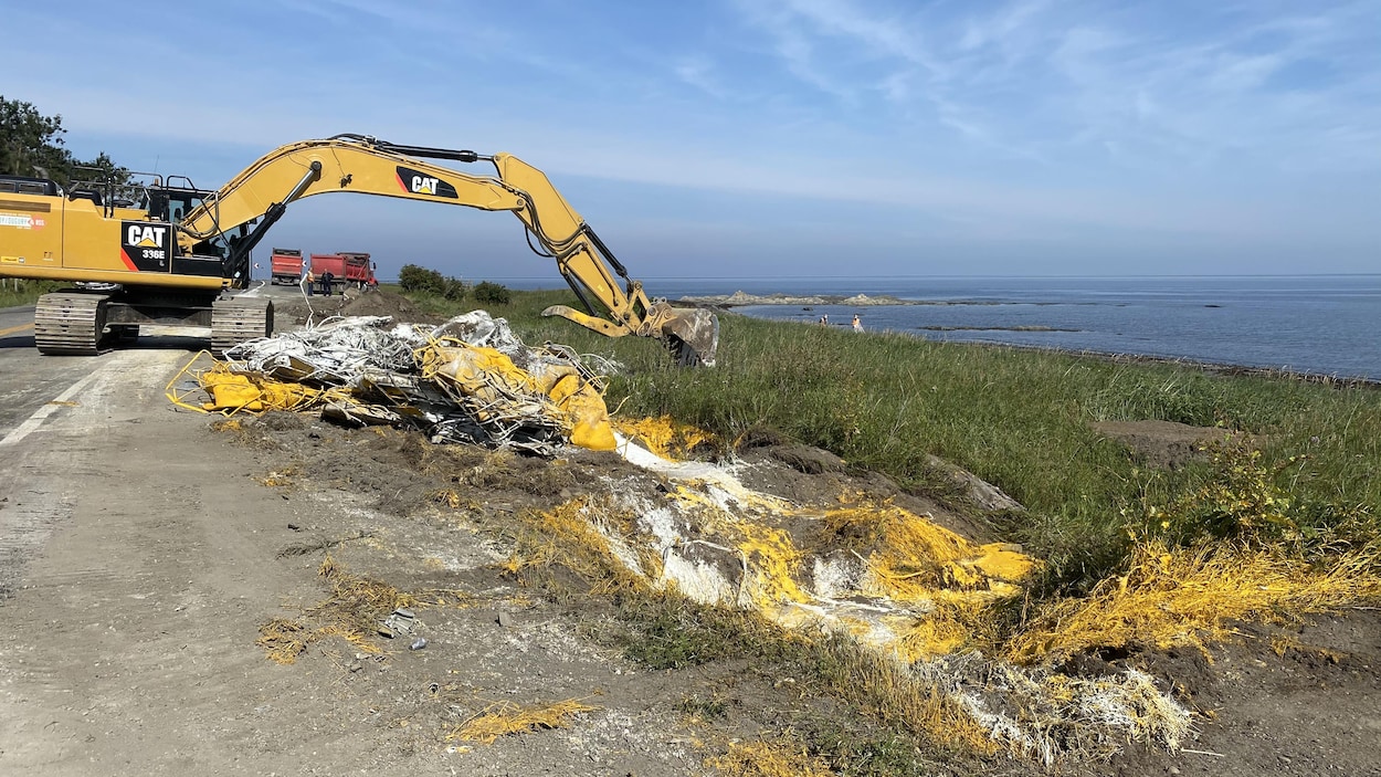 Une pelle mécanique ramasse les débris de l'accident et de la peinture colore les berges.