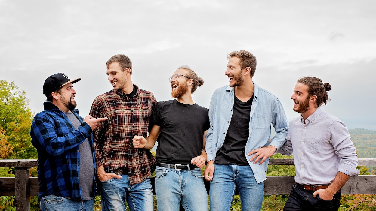 Cinq jeunes hommes dans la vingtaine et la trentaine sourient.