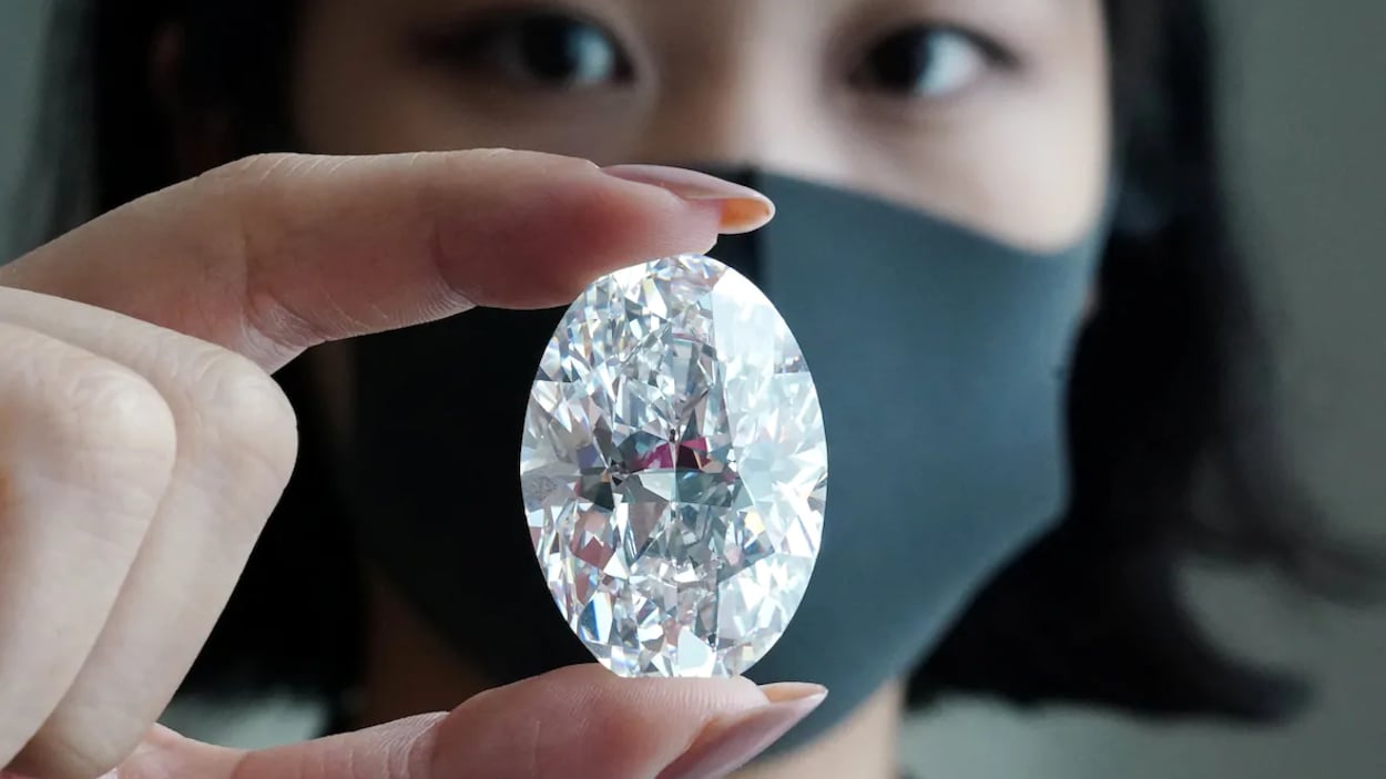 Une femme tient un diamant.