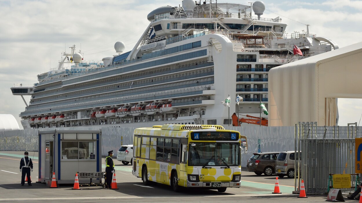Un autobus jaune franchit un point de contrôle devant le navire.