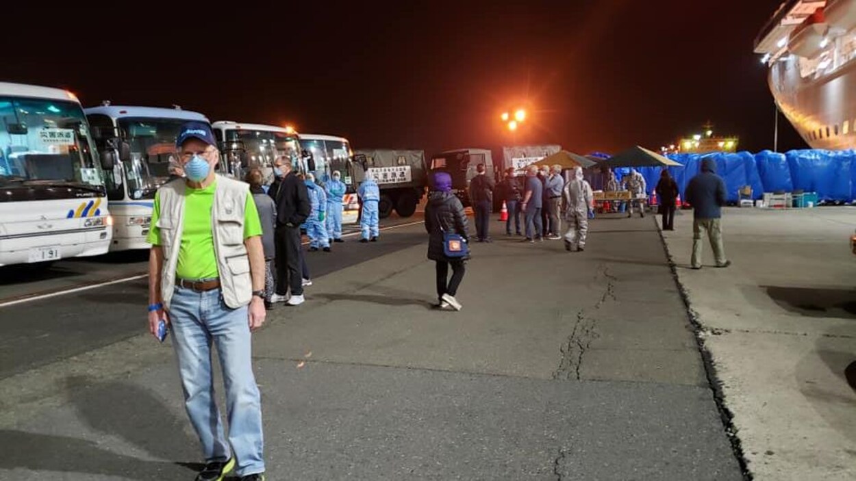 Des Canadiens parlent ou marchent devant une série d'autobus stationnées les uns à côté des autres.
