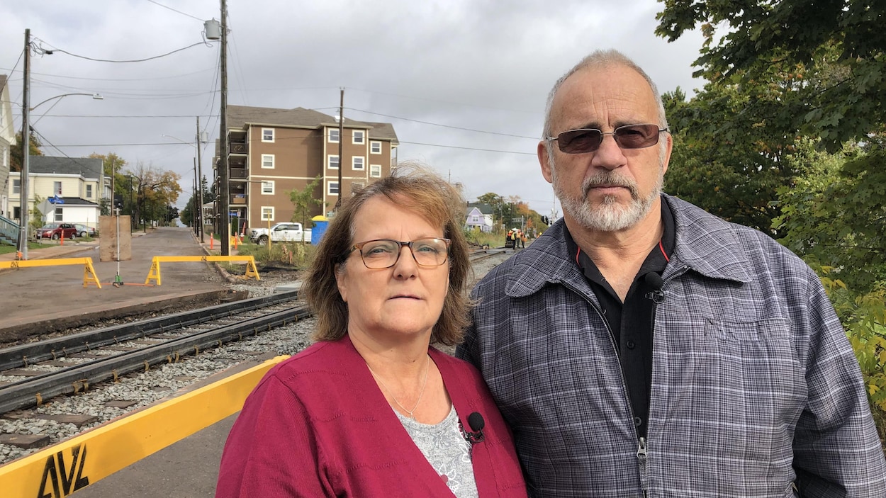Diane et Yvon Harel posent devant un passage à niveau.