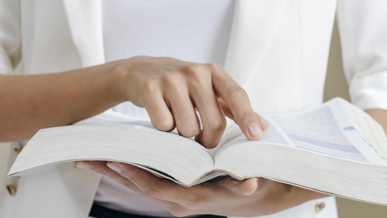 Une personne fait une recherche dans une dictionnaire.