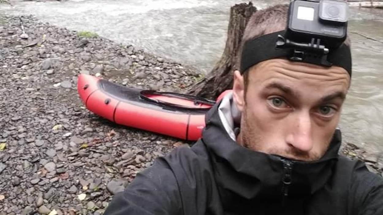 Le kayakiste se prend en photo sur une plage de galets avec son kayak gonflable.