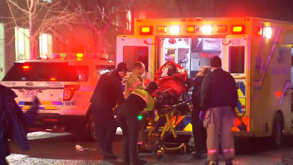 La victime sur une civière est placée dans une ambulance.