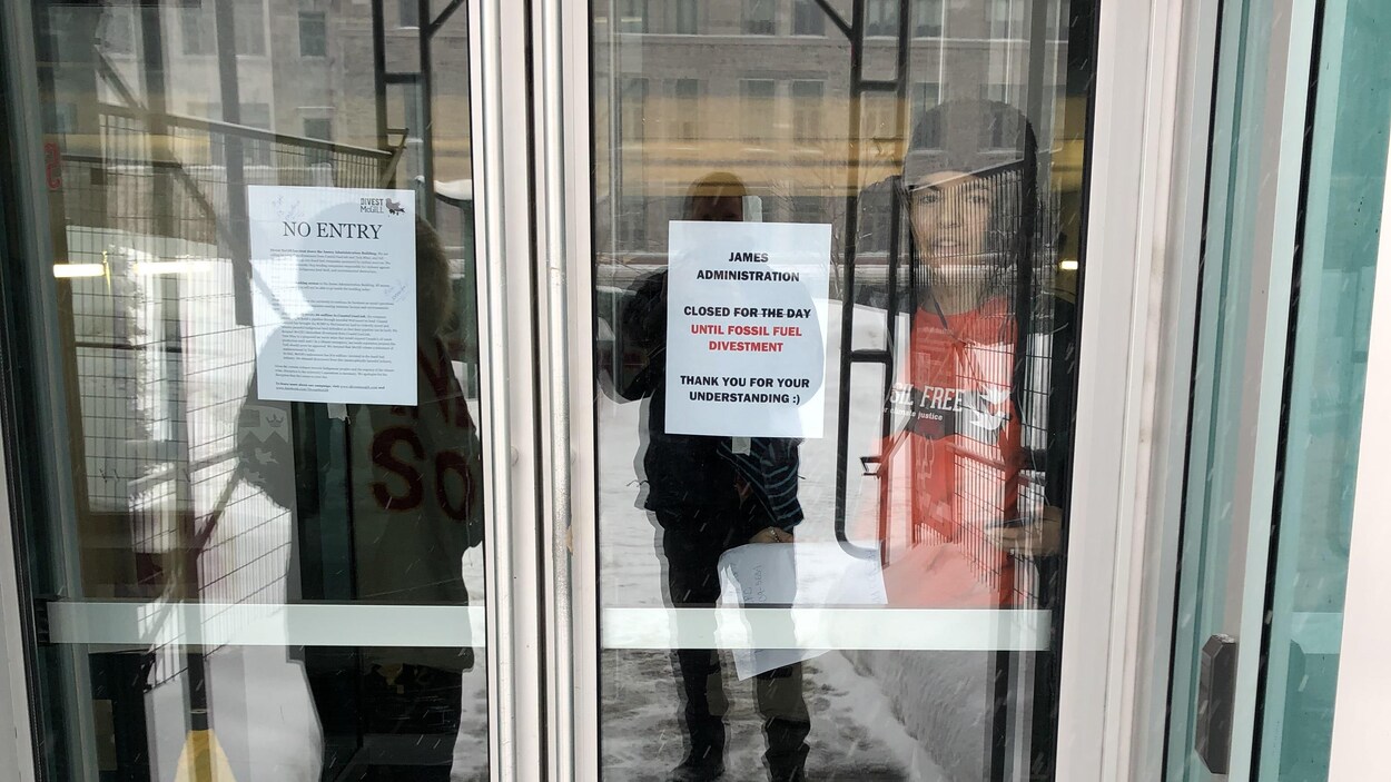 Une manifestante à l'intérieur d'un bâtiment sur les portes duquel sont collés des messages.